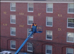 Furman employees take down SAE's letters off of the Lakeside Housing display of Greek life.